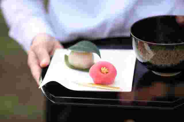 お盆の上に美味しい和菓子と抹茶を運ぶ店員