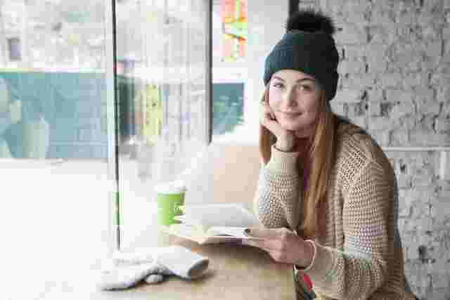 カフェの窓際で読書する女性