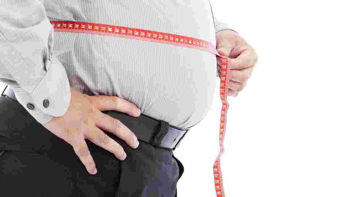 肥満気味の男性がお腹にメジャーを当てている様子