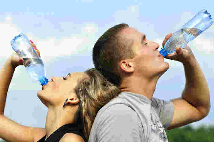 男女がペットボトルの水を飲んでいる様子