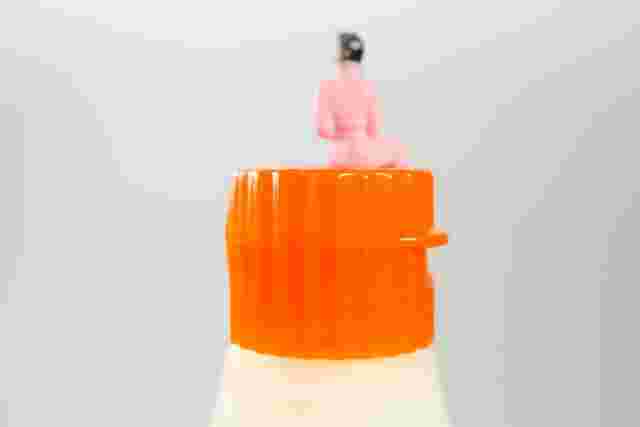 蓋のしまったマヨネーズの上に座る小さな女性の人形