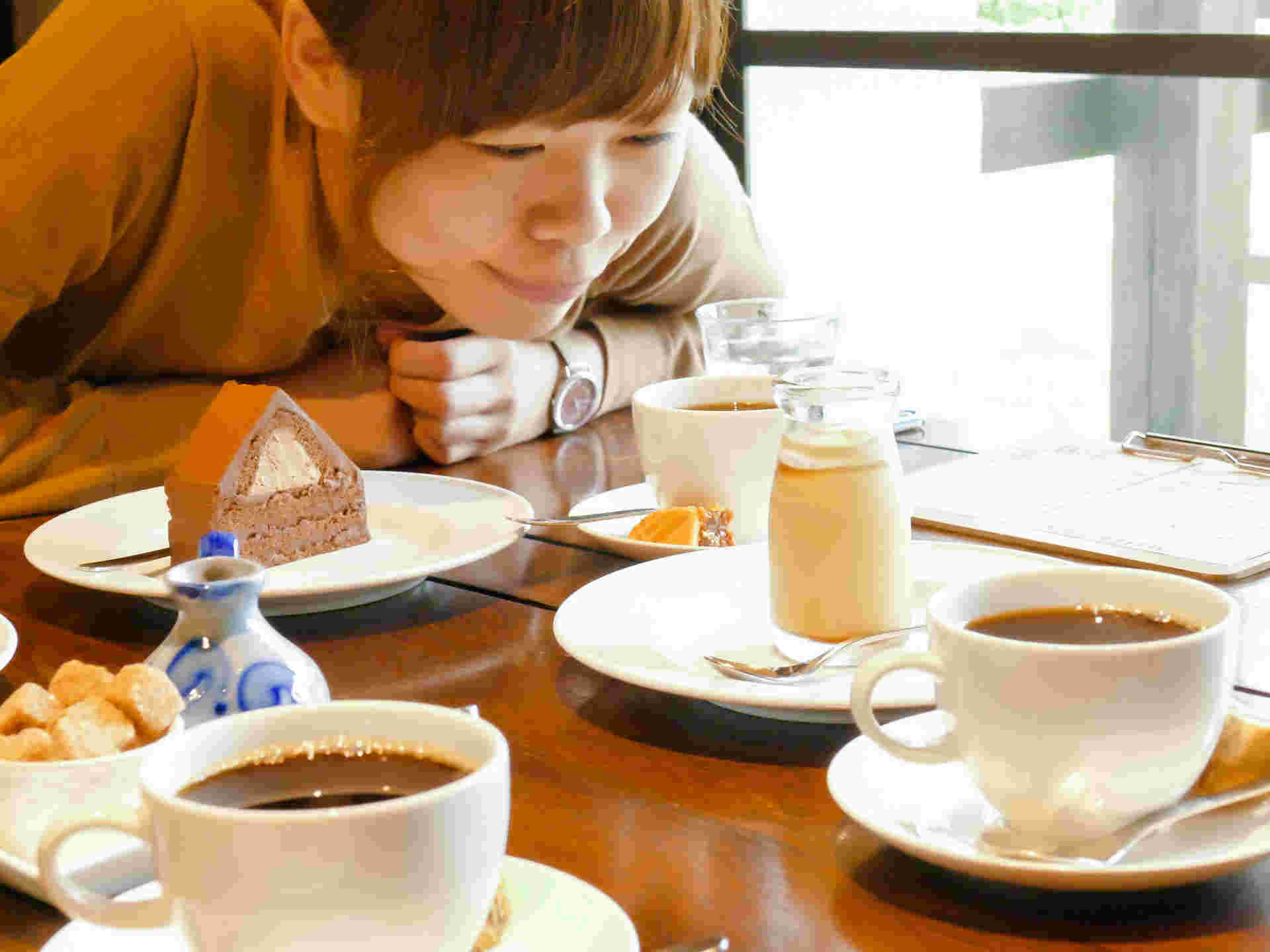 女性がテーブルで身を乗り出しコーヒーカップを見つめている店内