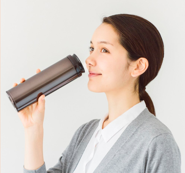 水筒で飲み物を飲んでいる女性