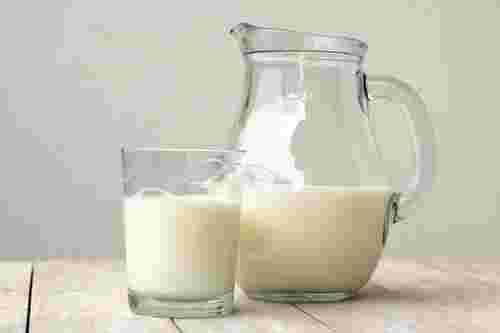 取っ手付きのビンに入った牛乳とグラスに入った牛乳