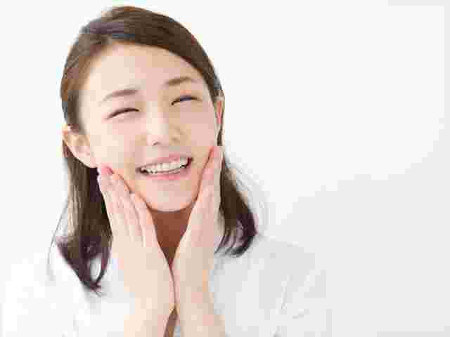 頬に手を当てて微笑む肌のきれいな女性