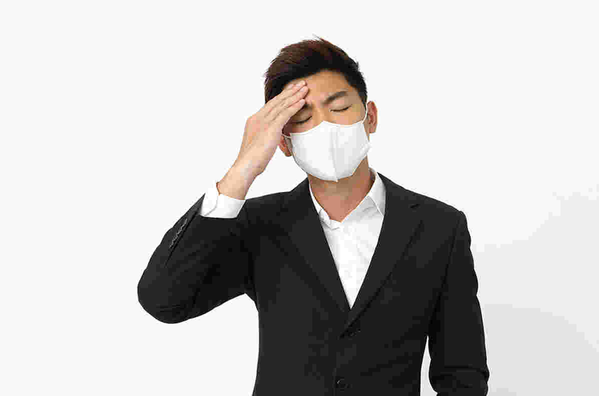 マスクをして額に手を当てる具合が悪そうな男性