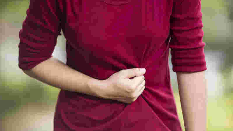 胃のあたりを押さえる女性の腹部