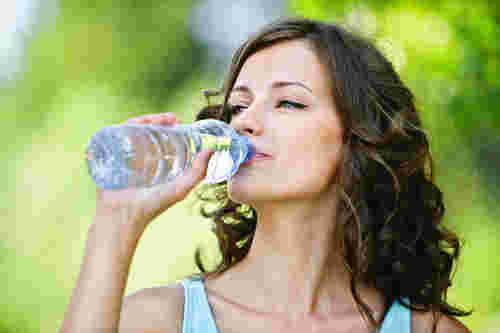 笑顔でペットボトルの水を飲む女性