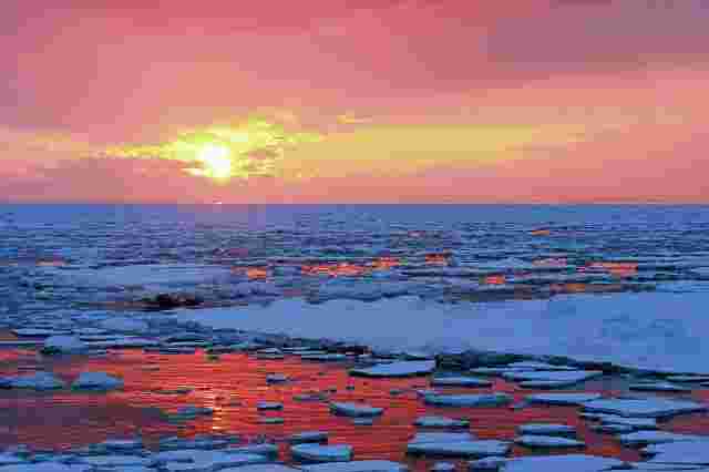流氷が流れている中、夕日が沈んでいく写真