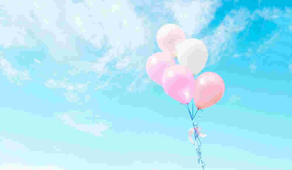 青空の中にピンク色の風船が5つ浮かんでいる様子