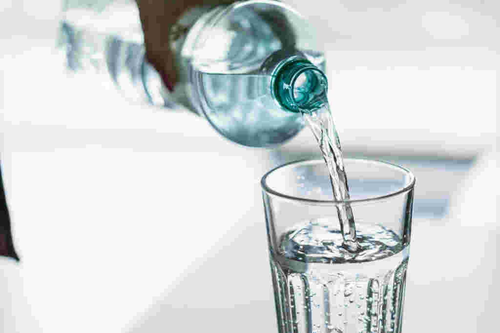 ペットボトルの水をコップに注ぐ様子