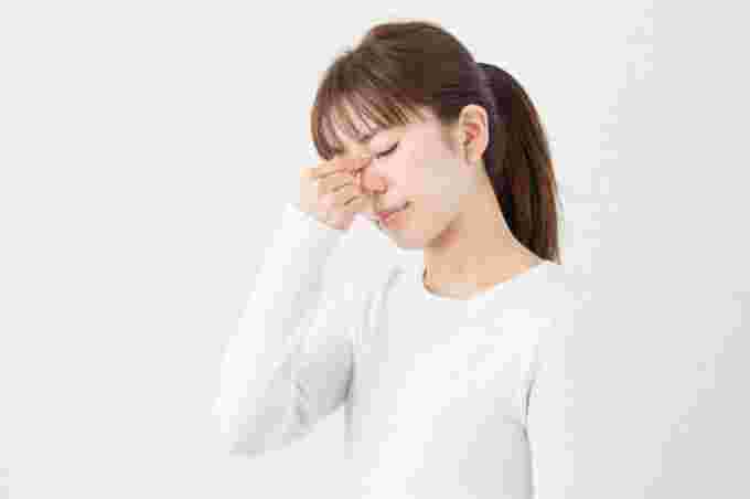 めまいがして眉間に手を当てている女性