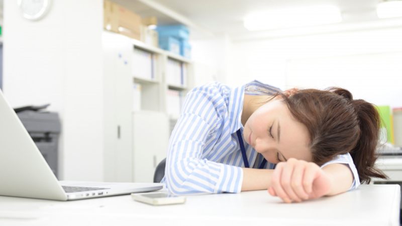 机の上でうつぶせになる女性
