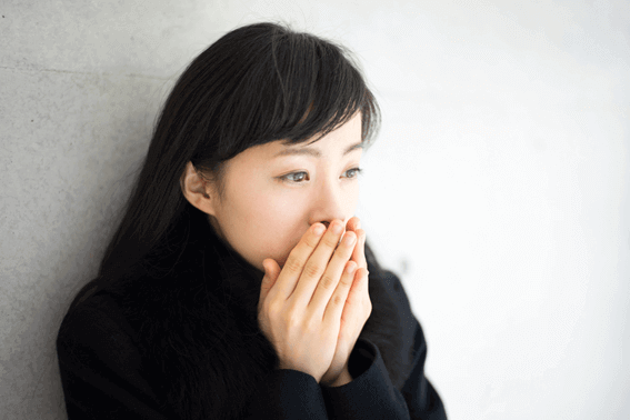 寒そうに手に息を吹きかけている女性