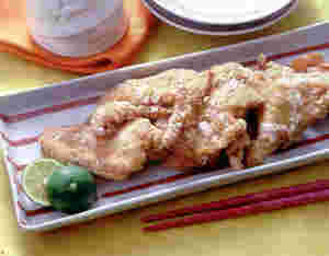 長方形の皿の上に鶏の竜田揚げがすだちと一緒に盛られている