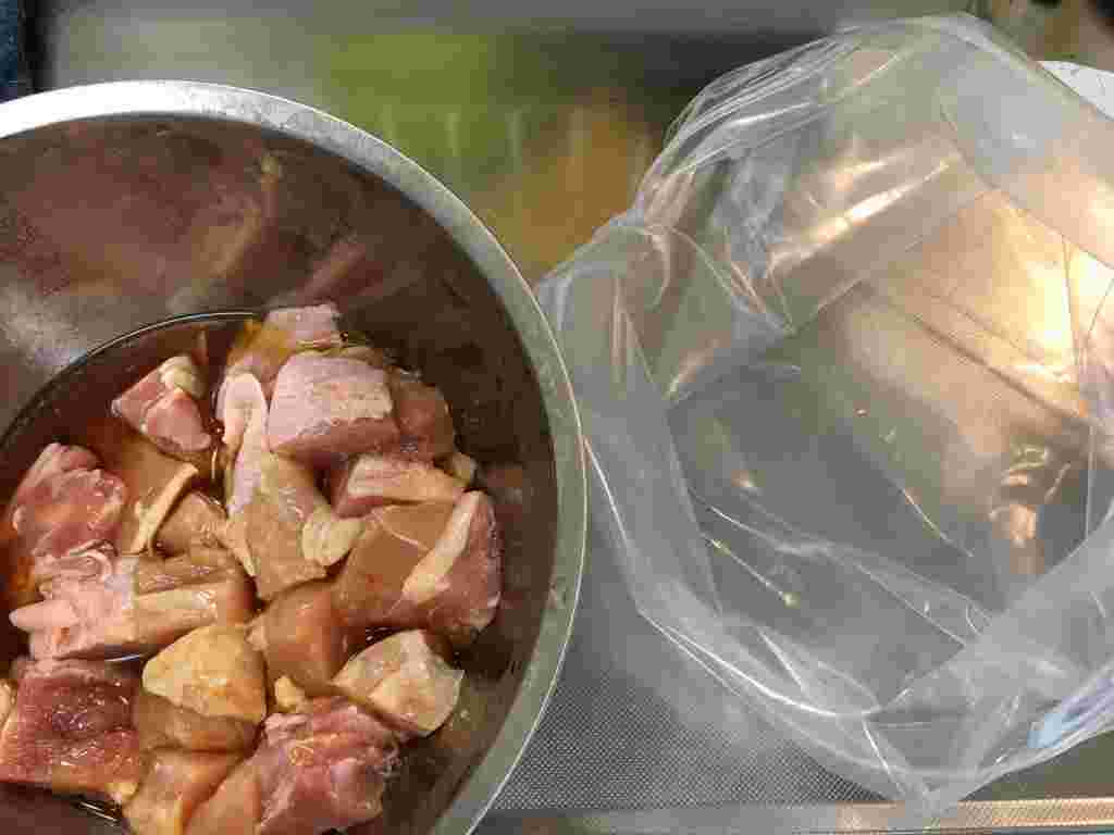 ボウルの中に鶏肉と下味をつけるための調味料が入っている。隣にはビニール袋が置かれている