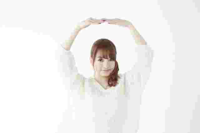 頭の上でOKサインをする女性