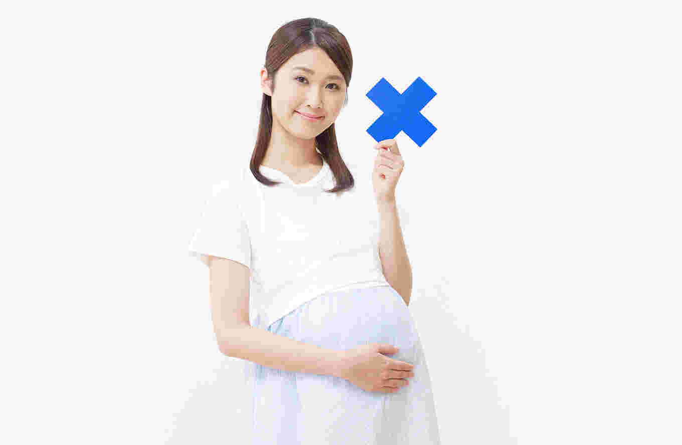 バツマークを持った妊婦