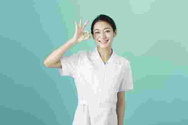白衣を着た女性がOKサインを出している様子