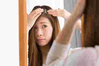 白髪が気になり鏡でチェックしている女性