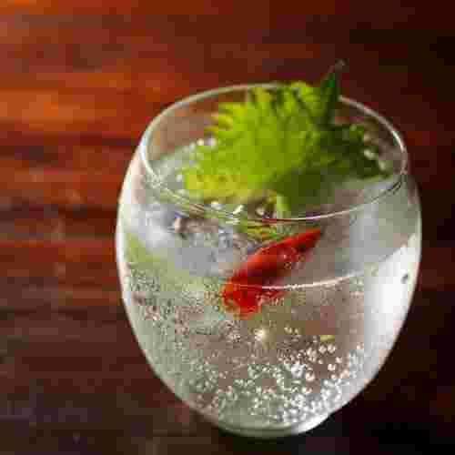 グラスの中に焼酎と鷹の爪と大葉が入っていてまるで金魚が泳いでいるように見える
