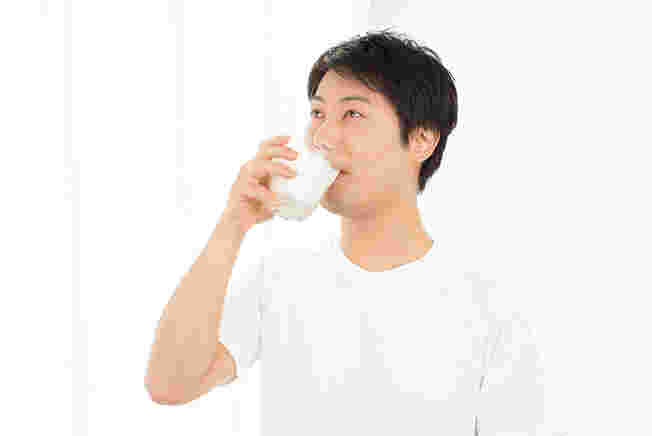 片手でグラスを持ち焼酎を飲んでいる男性