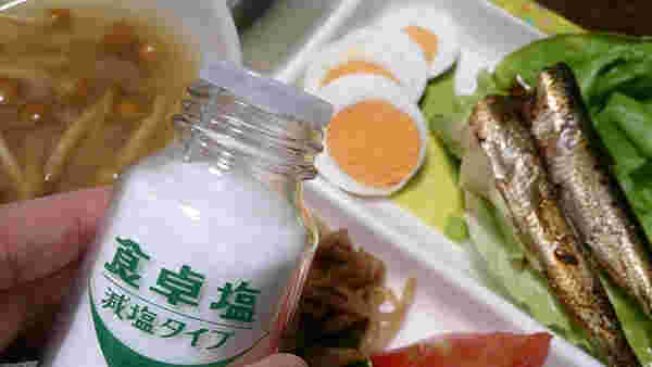食卓塩を料理にかけようとしている所