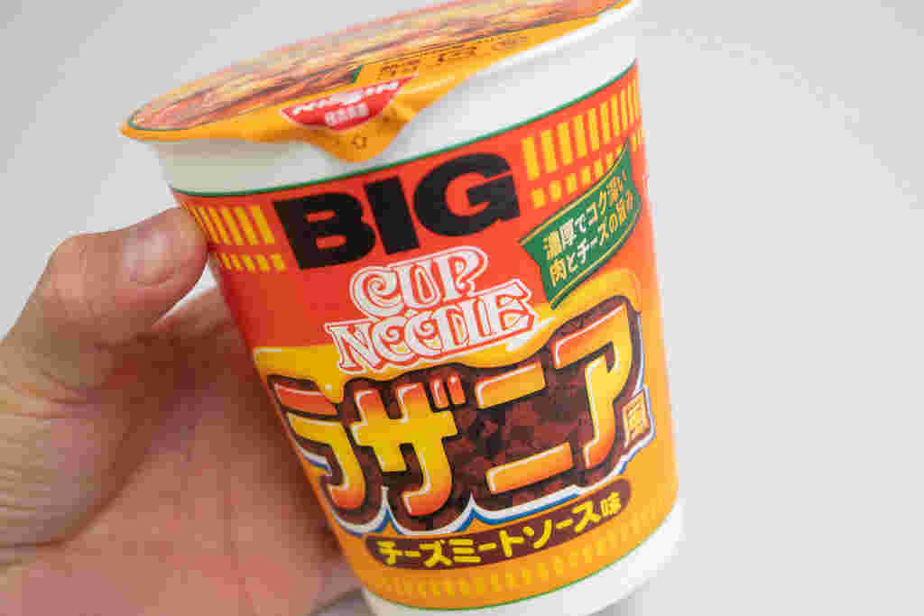 丸太型のカップ麺を片手でもっている