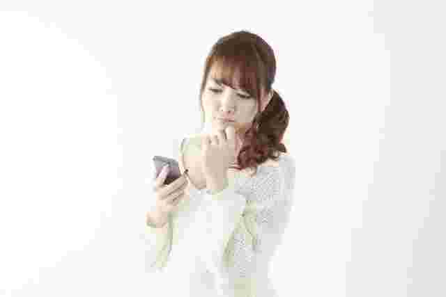 スマホを操作しながら悩む女性