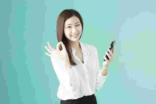 スマホを片手にOkサインを出す女性