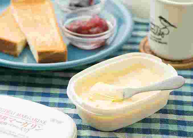 テーブルの上の皿にのった食パン、マーガリン、バターナイフ