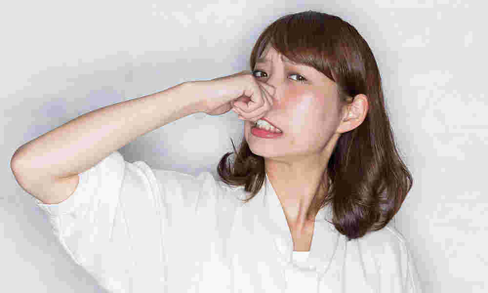 臭くて鼻をつまむ女性