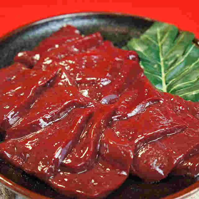 丸いお皿に盛りつけられているカットされている生レバーと葉っぱが綺麗に見える
