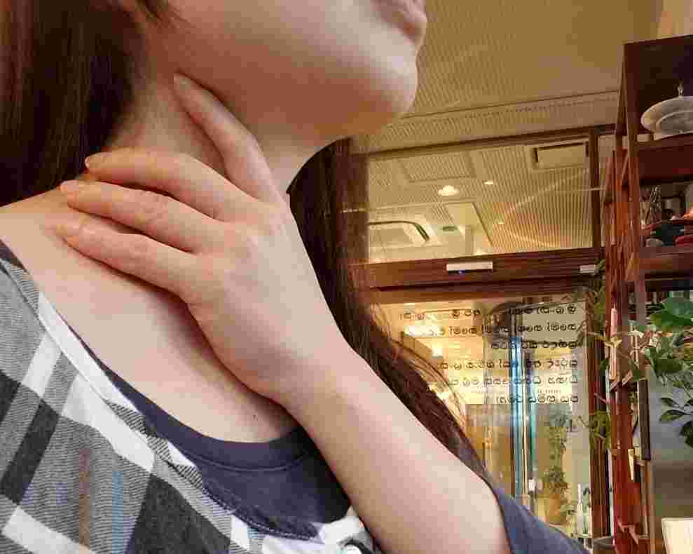 のどの痛みを感じて抑えている女性