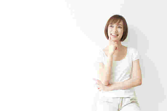 微笑みながら頬に指を当て考える女性