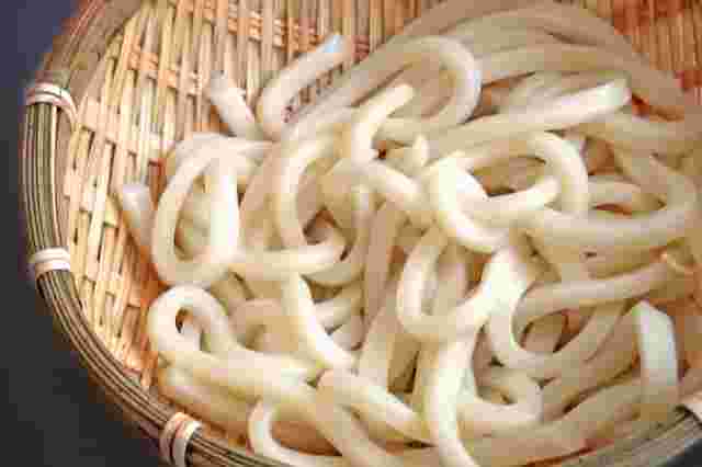 丸い竹ザルの上に多くのうどん麺がのせてある