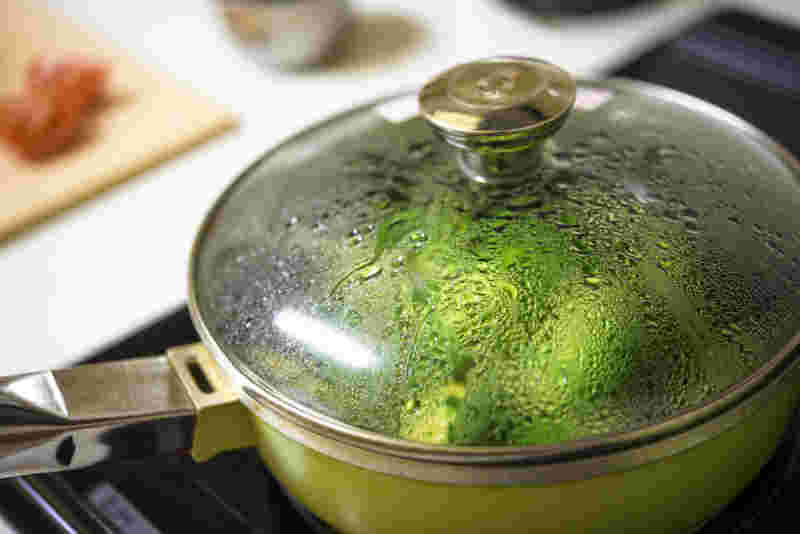 コンロの上の鍋で野菜が蒸されている