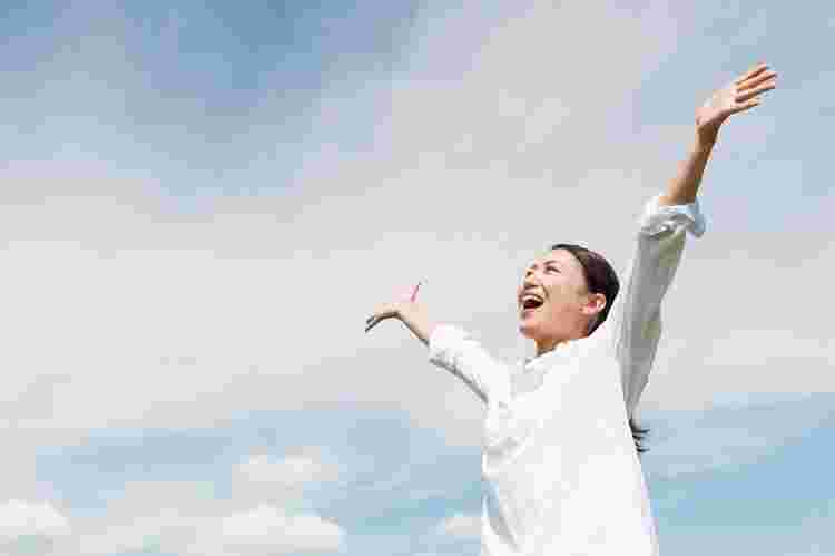空に向かって元気よく万歳する女性