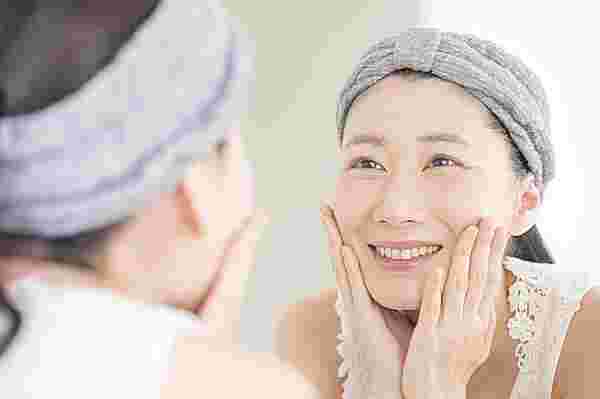 鏡を見つめてほほ笑む肌のきれいな女性