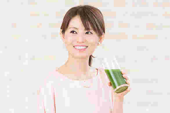 グリーンスムージーを飲んで笑顔の女性
