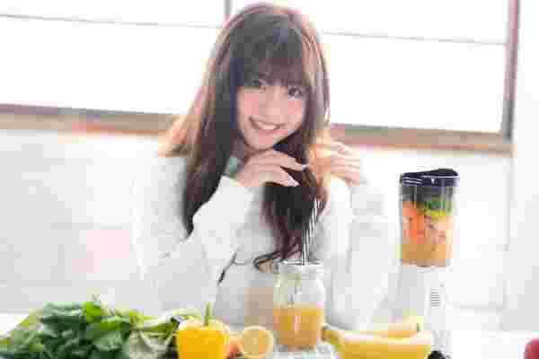 野菜ジュースを作って飲む笑顔の女性