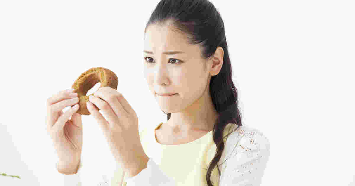 ドーナツを食べようか我慢しようか迷っている女性