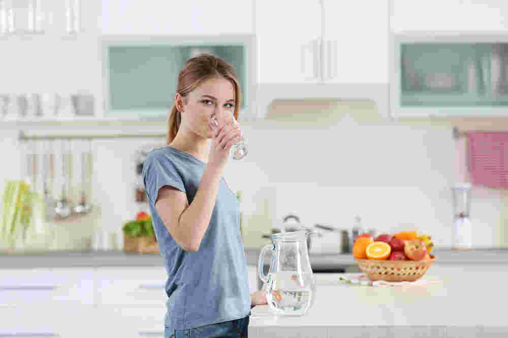 キッチンで水を飲む女性