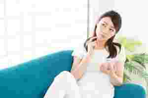 スマートフォンを手に持ち考えこむ女性