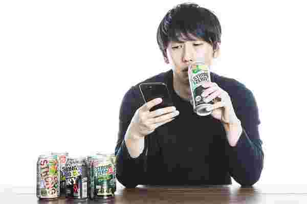寂しそうにストロングゼロを飲みながらスマホを見ている男性