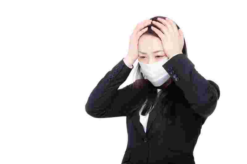 マスクをして頭を抱えている女性