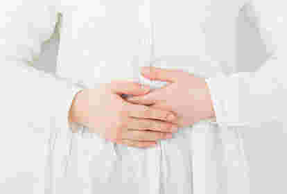 お腹を押さえる女性の腹部