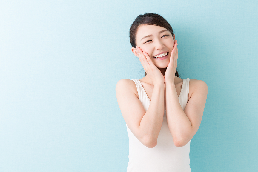 両頬に手を当て微笑む肌のきれいな女性