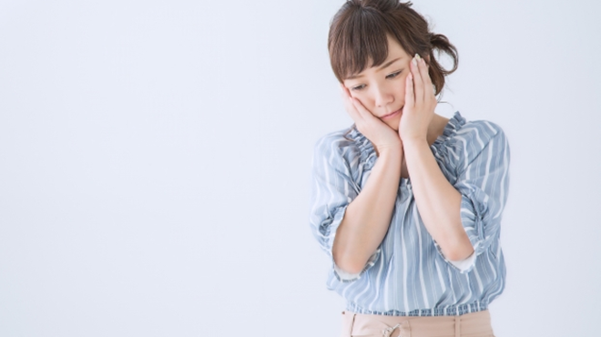 両手を頬に当て落ち込んだ表情の女性