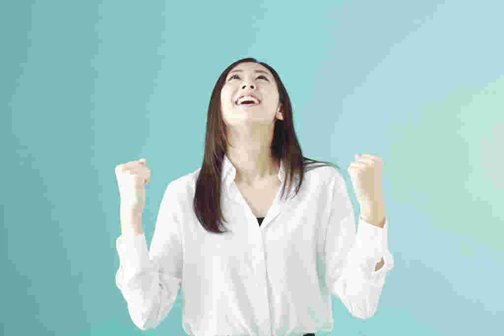 天に顔を向けてガッツポーズをする女性